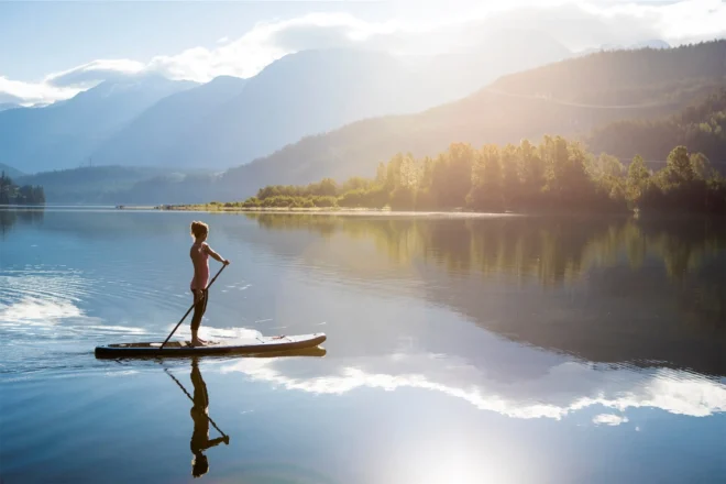 Paddleboarding alone on a calm lake in Whistler with mountain views